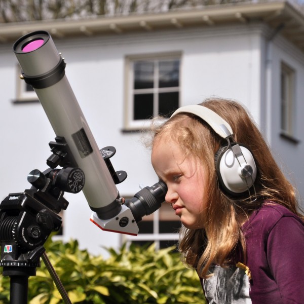 Een meisje kijkt door een telescoop naar de zon in de tuin van Sonnenborgh
