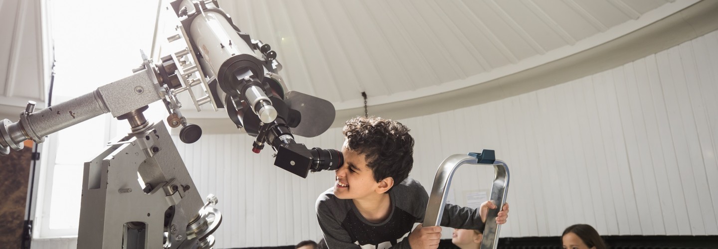 Jongetje kijkt door een telescoop